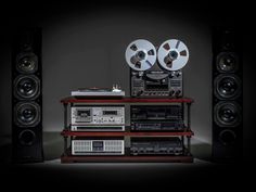 an old fashioned stereo system with two reels on top of it and some speakers behind it