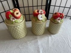 three ceramic apples in baskets on a table