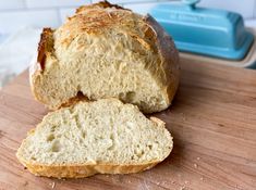 a loaf of bread sitting on top of a wooden cutting board next to a blue container