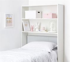 a white book shelf above a bed with pillows and blankets on it's sides