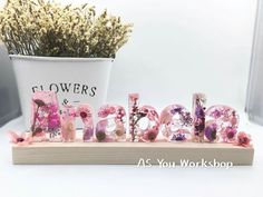 a flower shop sign sitting on top of a wooden shelf next to a potted plant