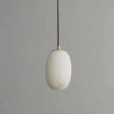 a white and gold light hanging from a black cord on a gray wall in a room