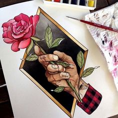 a drawing of a hand holding a rose on top of a piece of paper with watercolor pencils next to it