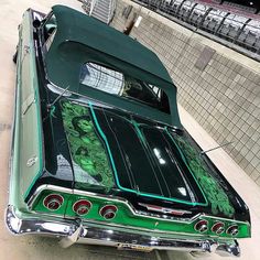 an old green car is parked on the side of the road with its hood up