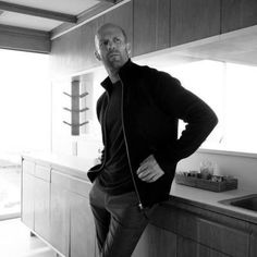 a man leaning on a counter in a kitchen with his hands on his hips and looking at the camera