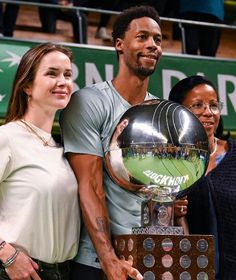 two women and a man holding a basketball trophy in front of a green banner with the words espn on it