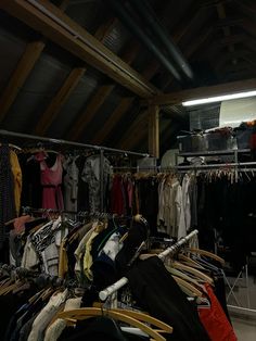 an attic with clothes hanging on racks and other items