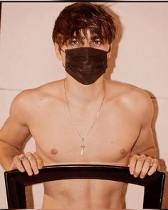 a shirtless man wearing a black face mask and holding a chair with his hands