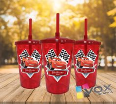 three red tumblers with cars on them are sitting on a wooden table in front of the sun