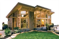 a small house with lots of windows and grass in front of the entrance to it