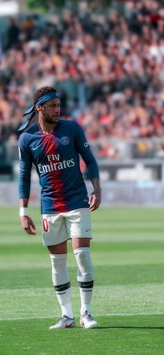 a man standing on top of a field next to a soccer ball in front of a crowd