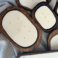 four wooden trays filled with white candles on top of a cloth covered tablecloth