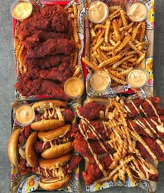 several trays of food including hot dogs, french fries and other condiments