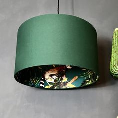 a green lampshade hanging from the ceiling next to a cactus plant