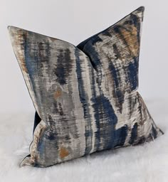 two blue and brown pillows sitting on top of a white furnishce floor next to each other