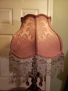 a lamp that is sitting on top of a table in front of a door with a pink shade