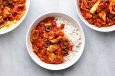 three white bowls filled with food on top of a table next to another bowl full of rice