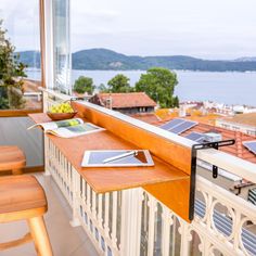 a balcony with a table and chairs on it, looking out over the water from an apartment