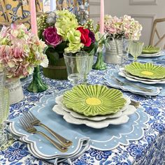 the table is set with plates, silverware and vases filled with colorful flowers