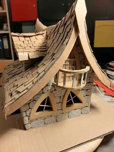 a cardboard house made to look like it is on top of a table with books