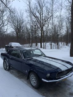 an old mustang car is parked in the snow