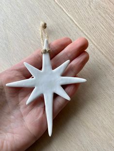 a hand holding a white ceramic star ornament