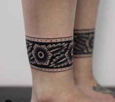 a woman's foot with a black and white tattoo design on her left ankle