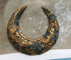 a gold and black crescent shaped object sitting on top of a white shelf next to a wall