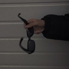 a woman holding onto a pair of sunglasses in front of a garage door with her hand on the side of the glasses