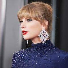 a woman in blue dress with large earrings on her head and red lipstick, posing for the camera