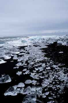 ice floes floating on the water next to an ocean shore with large chunks of ice