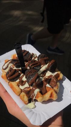 someone is holding up a waffle with chocolate and cream on it