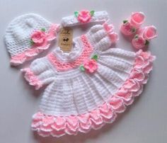 a crocheted baby dress and hat with pink flowers