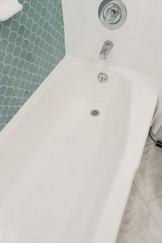 a white bath tub sitting in a bathroom next to a toilet paper dispenser