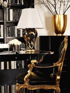 a gold vase sitting on top of a table next to a black book shelf filled with books