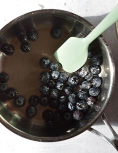 blueberries are in a saucepan with a green spoon