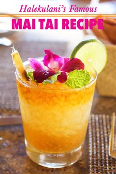 a tall glass filled with orange juice and garnished with pink flowers on the rim