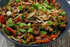 a blue bowl filled with stir fry vegetables