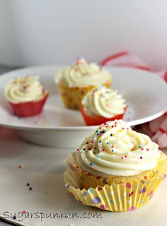 cupcakes with white frosting and sprinkles on plates