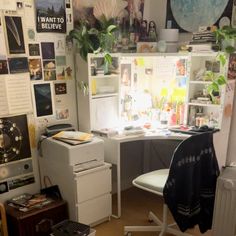 a room with a desk, refrigerator and various pictures on the wall