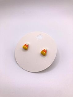 two orange and yellow candy corn earrings on a white plate