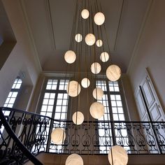 a chandelier hanging from the ceiling in a room with large windows and wrought iron railings