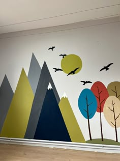 a wall painted with trees and mountains on it's sides, birds flying in the sky