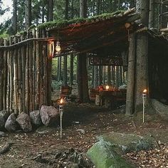 an outdoor dining area in the woods with candles lit up on rocks and wood logs