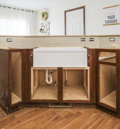 a kitchen with wooden cabinets and a white sink in the center is under an open cabinet door