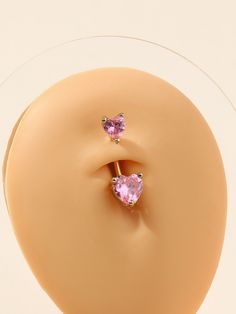 two pink heart shaped earrings sitting on top of a plastic object in front of a white background