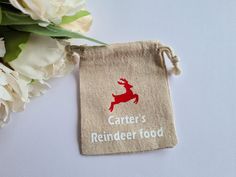 a bag with a deer on it sitting next to some flowers and white carnations