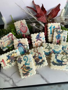 decorated cookies with numbers on them sitting on a marble counter top in front of some plants