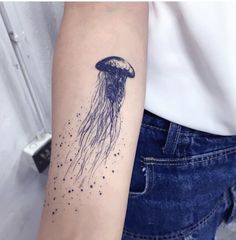 a woman's arm with a black ink jellyfish tattoo on it