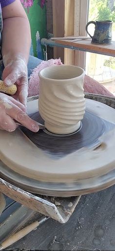 a woman is making a pottery bowl on a potter's wheel with her hands